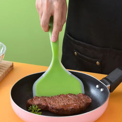 Spatule verte qui tourne un morceau de steak